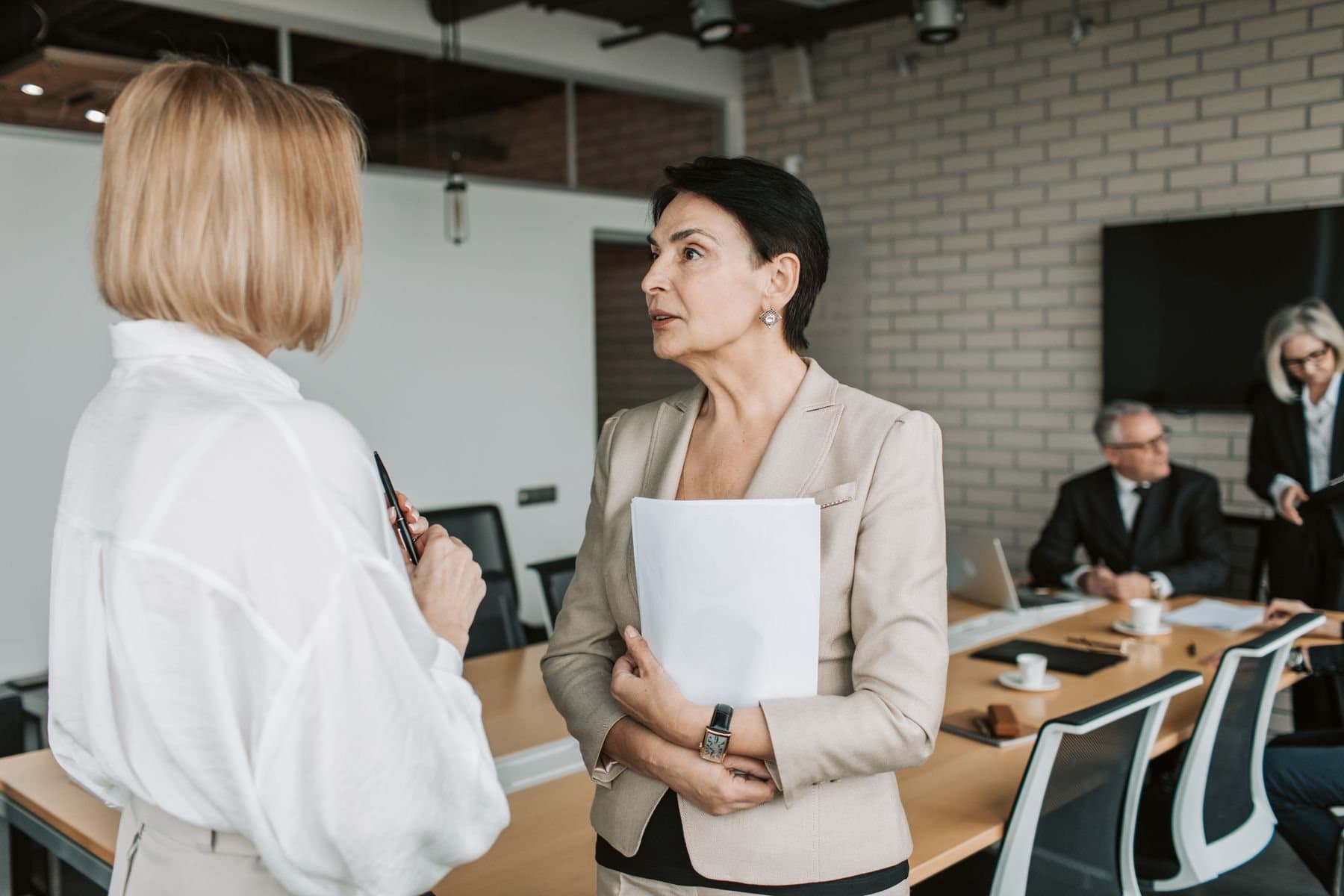 Two colleagues in conversation beside a meeting room