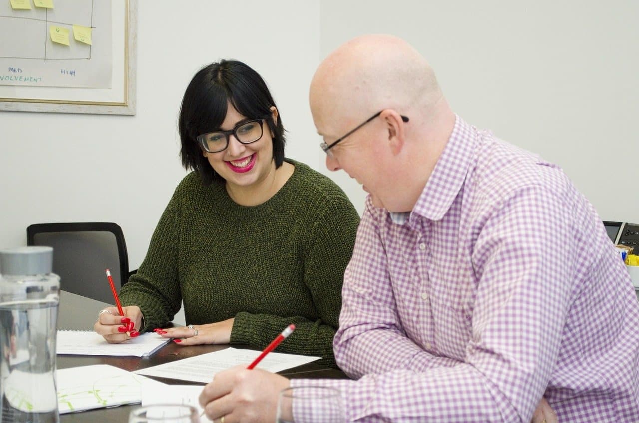 Two colleagues marking up printed sheets side by side