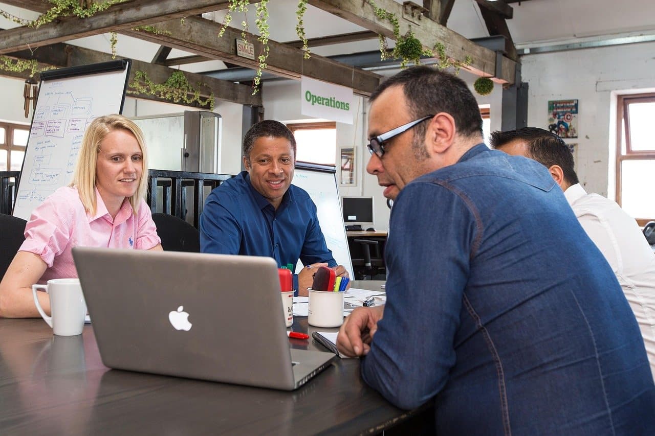 A group gathered around one laptop at a shared table