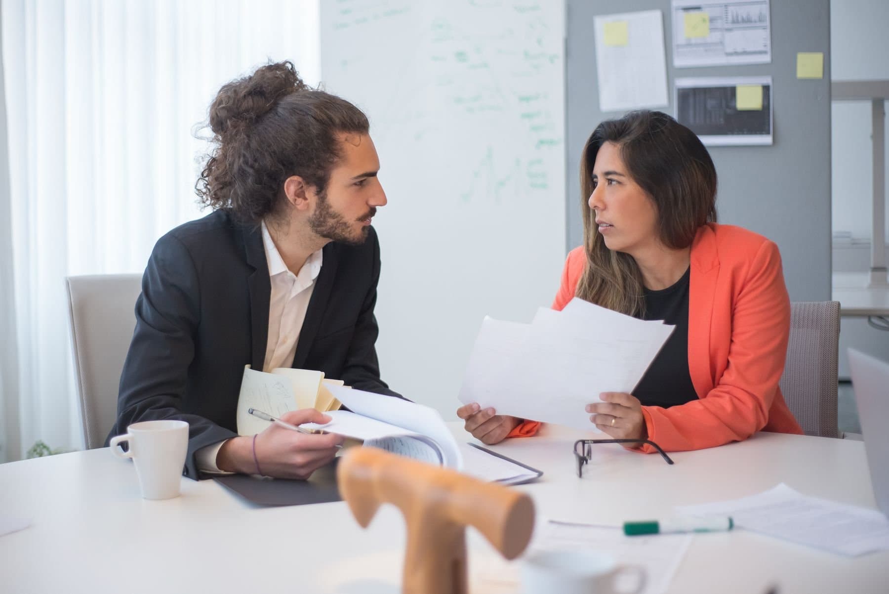 Two colleagues working through printed documents at a desk