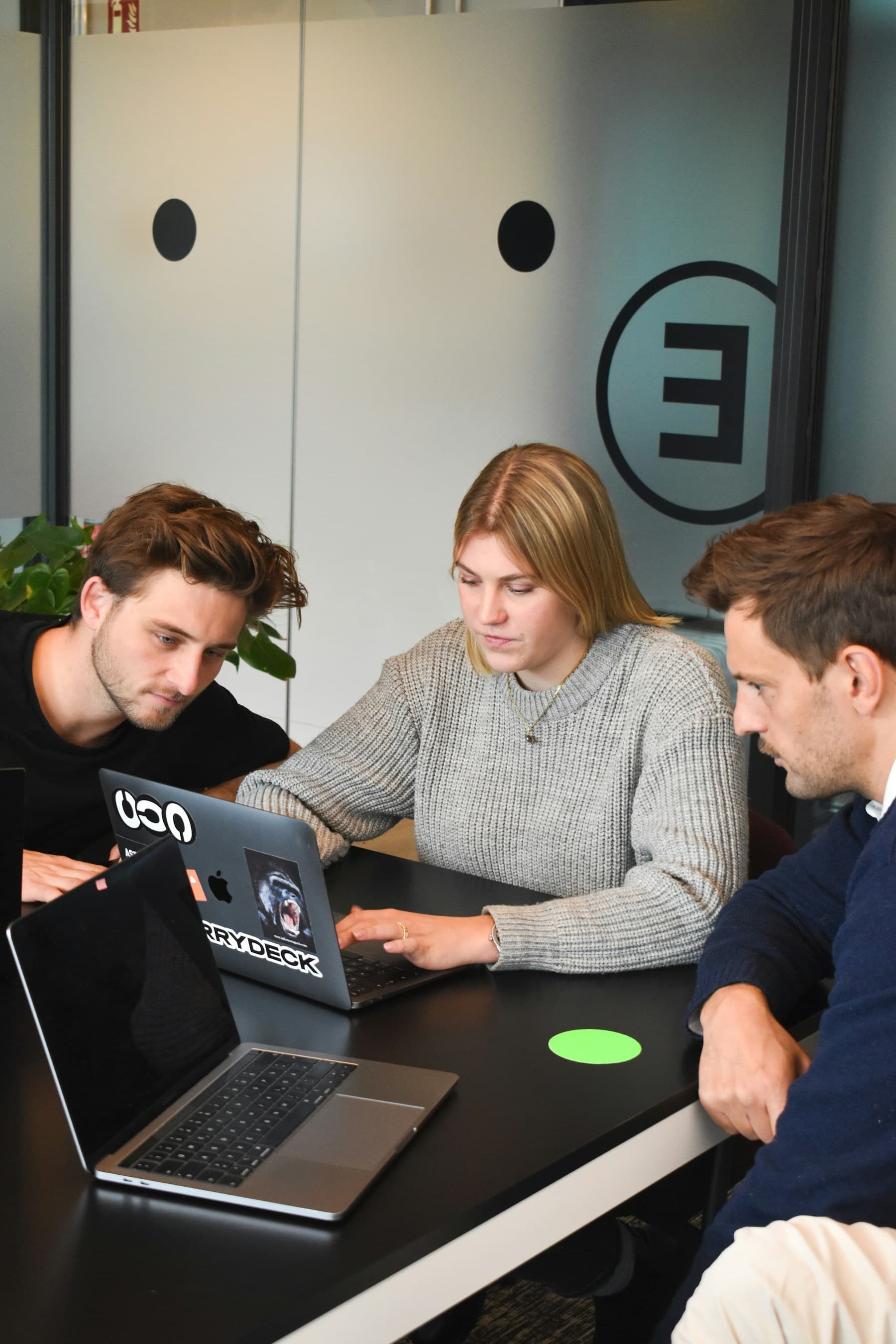 Four colleagues gathered around a laptop, working through something together